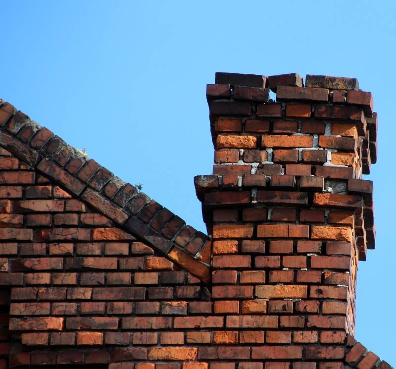 Damaged chimney on an Costa Mesa home showing cracks and missing mortar